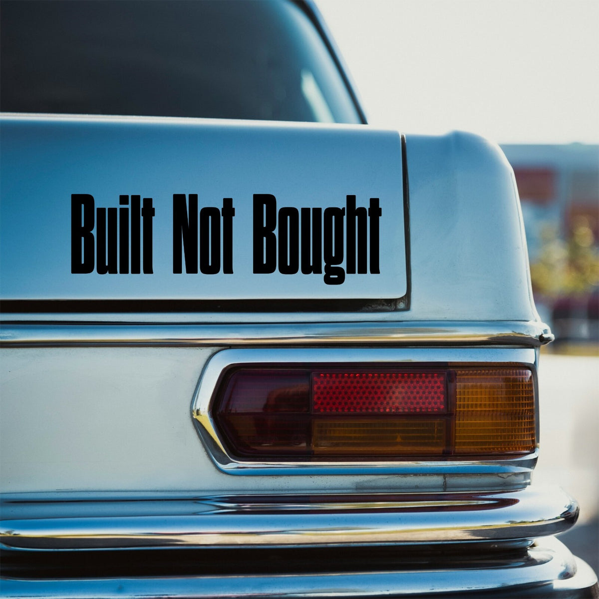 Black Built Not Bought tall lettering decal on the rear of a turquoise campervan.