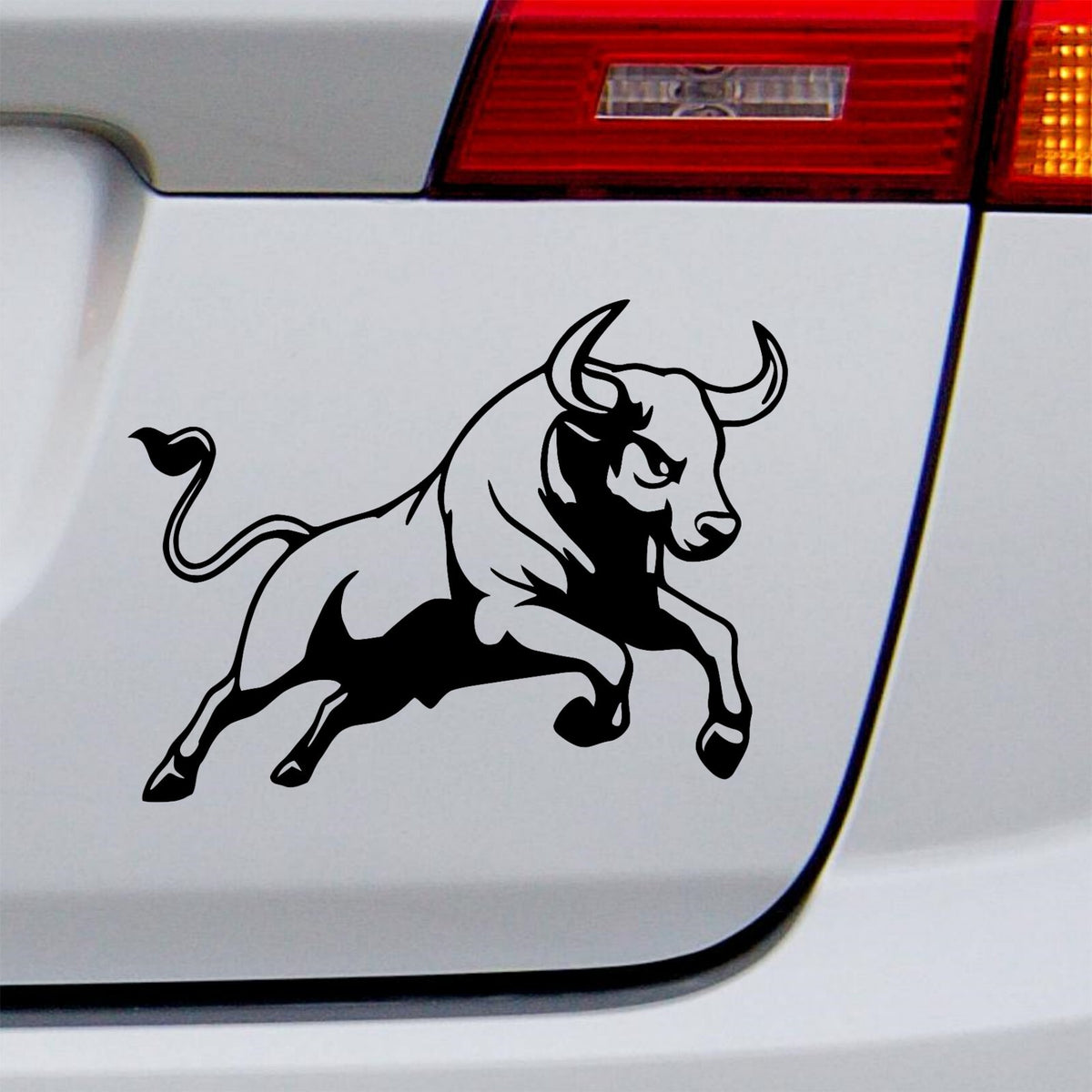 Black charging bull decal on a white vehicle tailgate.