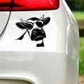 Black cow with sunglasses sticker on white car bodywork beneath a rear light.