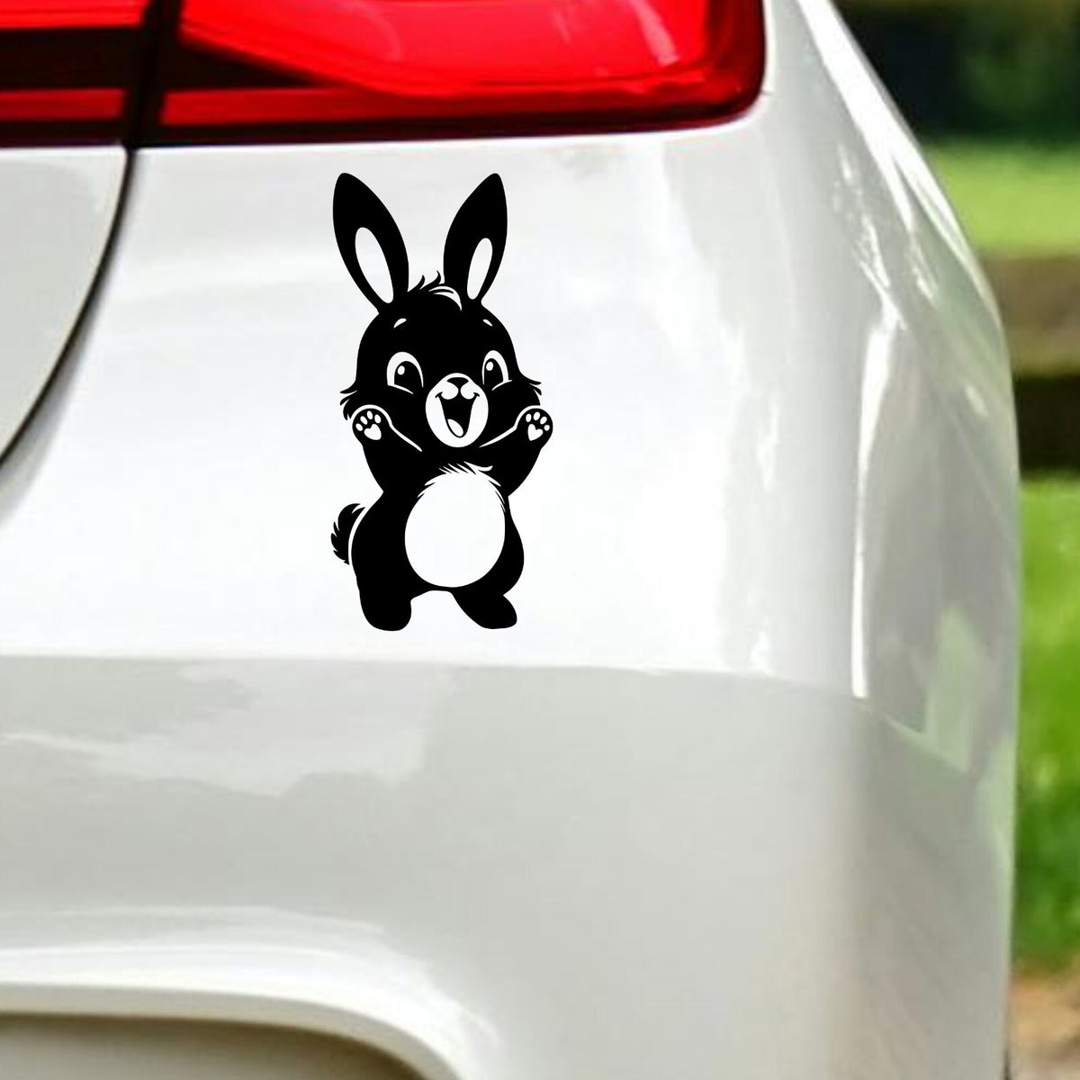 Black cute bunny rabbit sticker on white car bodywork beneath a rear light.