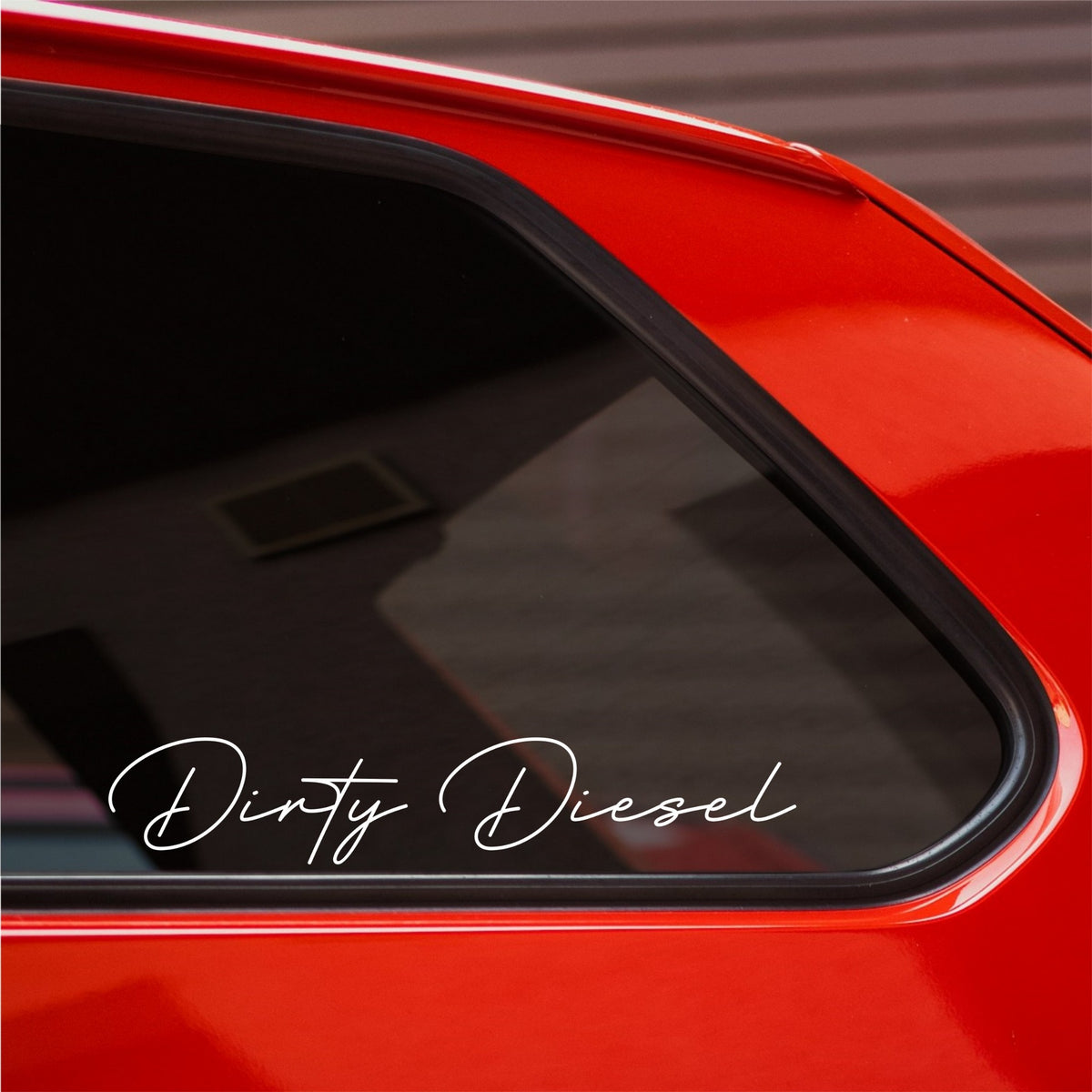 White Dirty Diesel car sticker in fine flowing script on a red car's rear side window.
