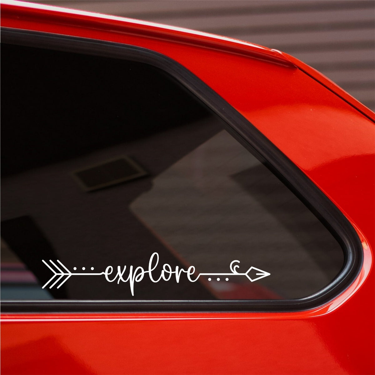 White Explore arrow decal on the rear side window of a red car.