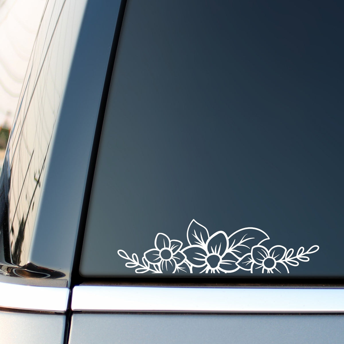 White floral flower border sticker along the bottom of a vehicle side window.