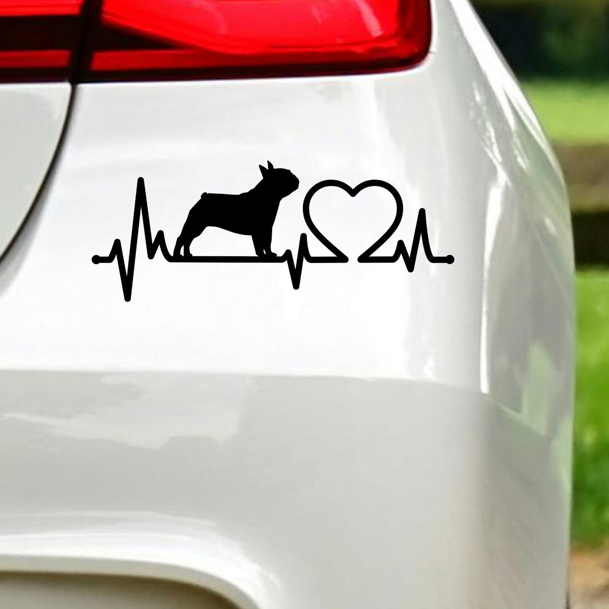 Black french bulldog heartbeat sticker on white car bodywork beneath a rear light.