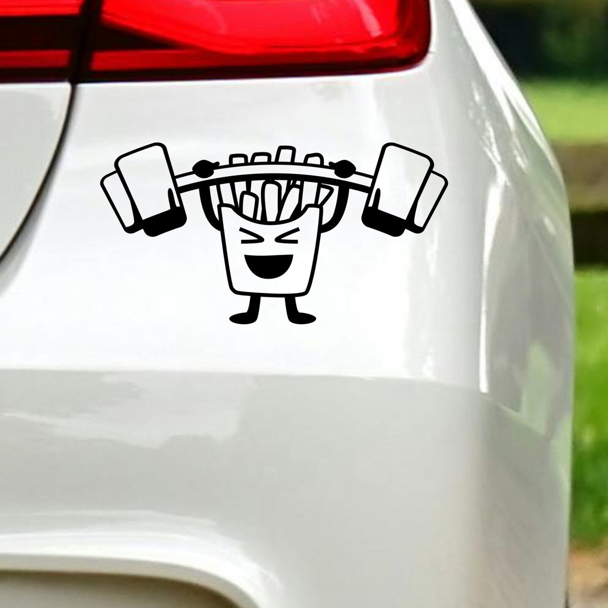 Black french fries barbell sticker on white car bodywork beneath a rear light.