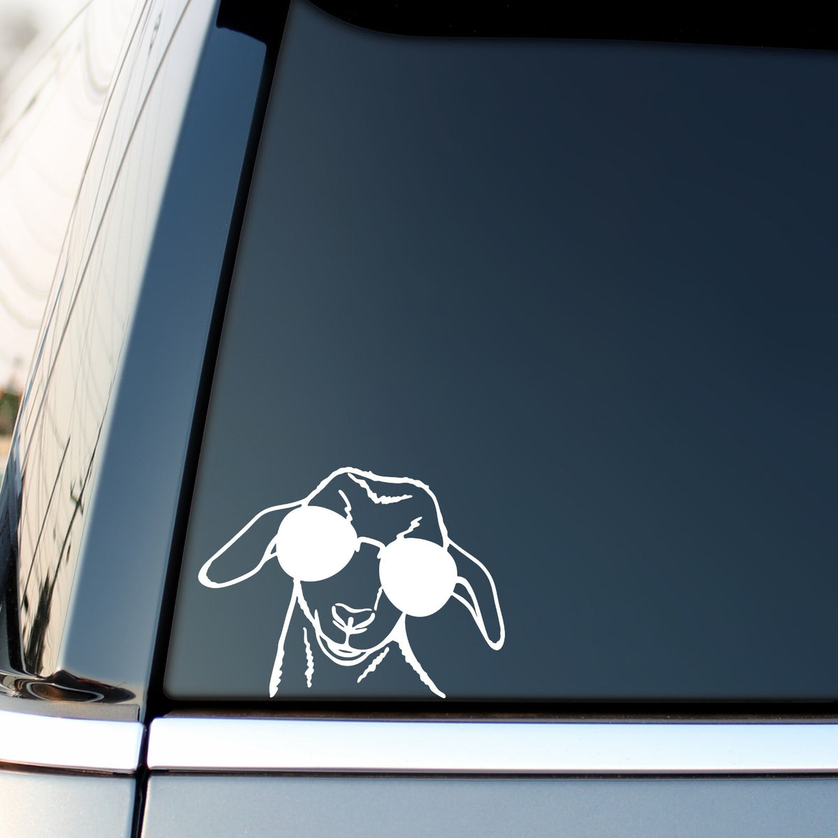 White goat with sunglasses sticker on a vehicle side window.