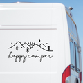 Happy Camper script beneath mountains, trees and stars on a white caravan.