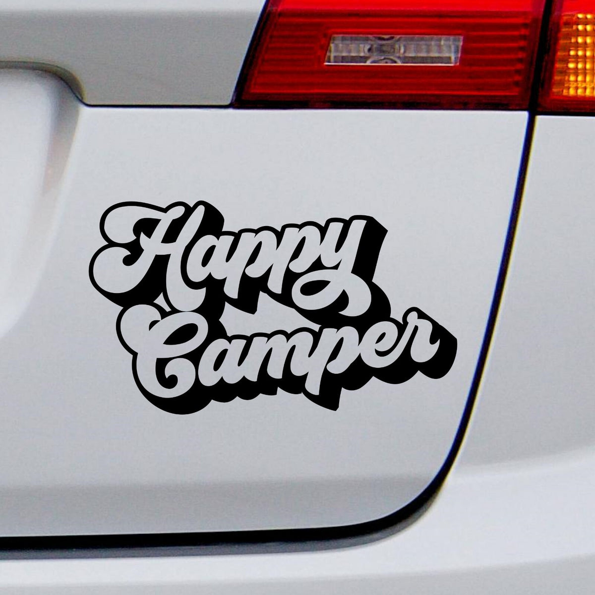 Black Happy Camper outline lettering decal on a white car rear panel.
