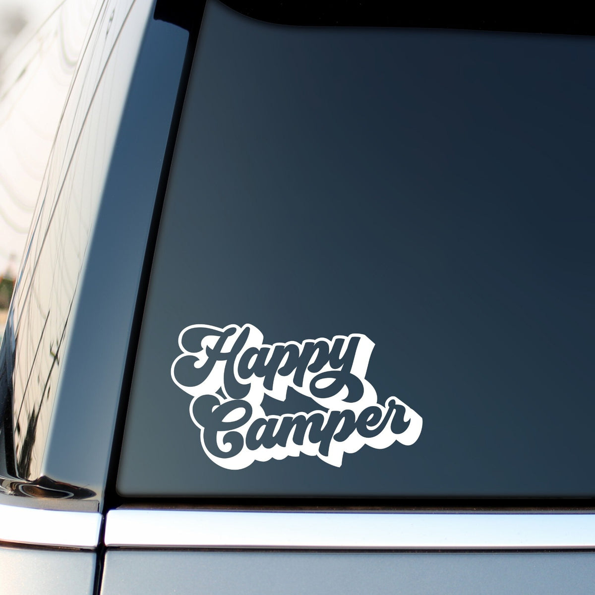 White Happy Camper outline lettering decal on a car side window.
