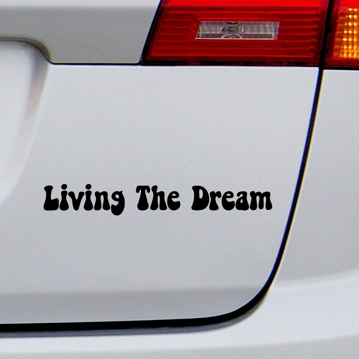 Black Living The Dream retro lettering decal on a white car rear panel.