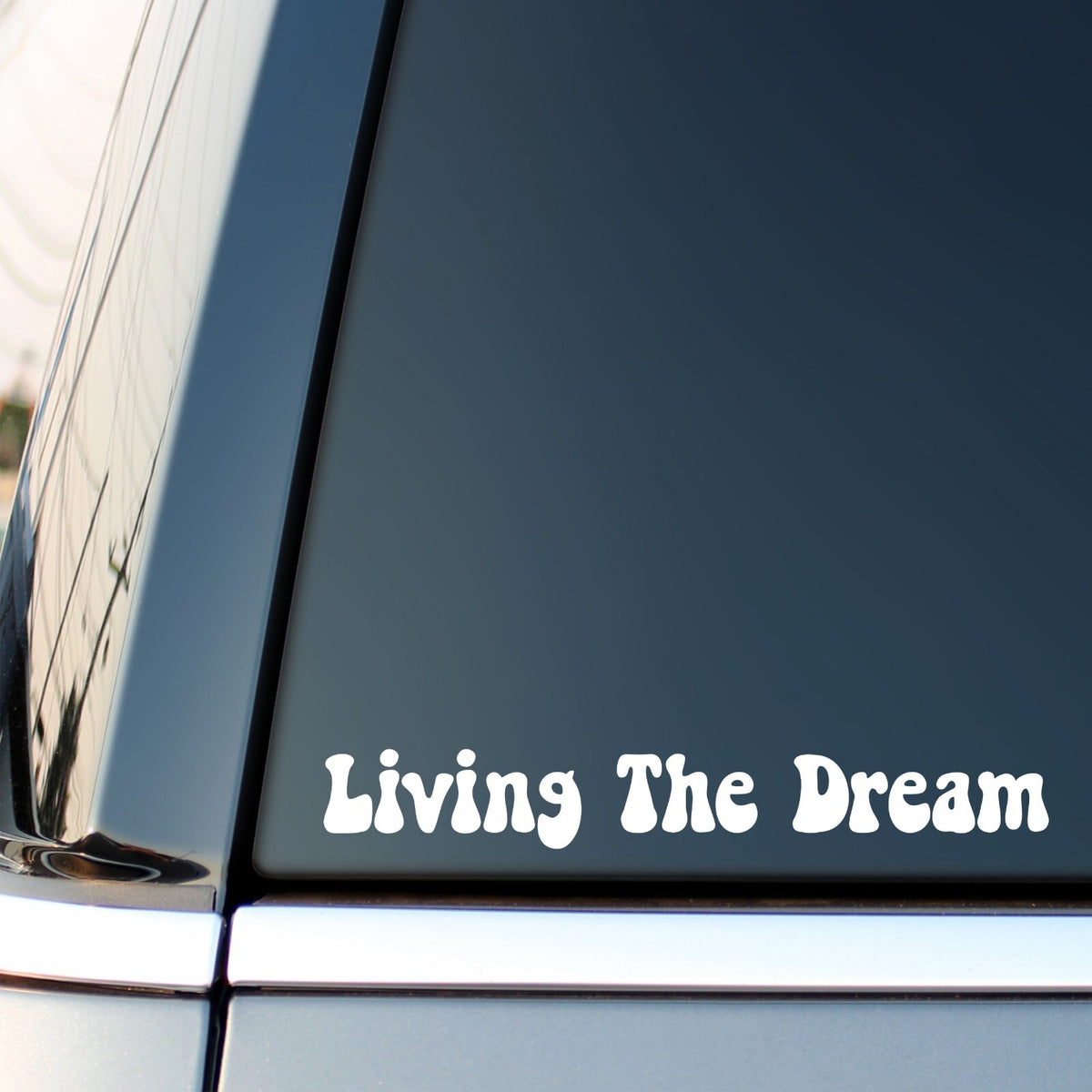 White Living The Dream retro lettering decal on a car side window.