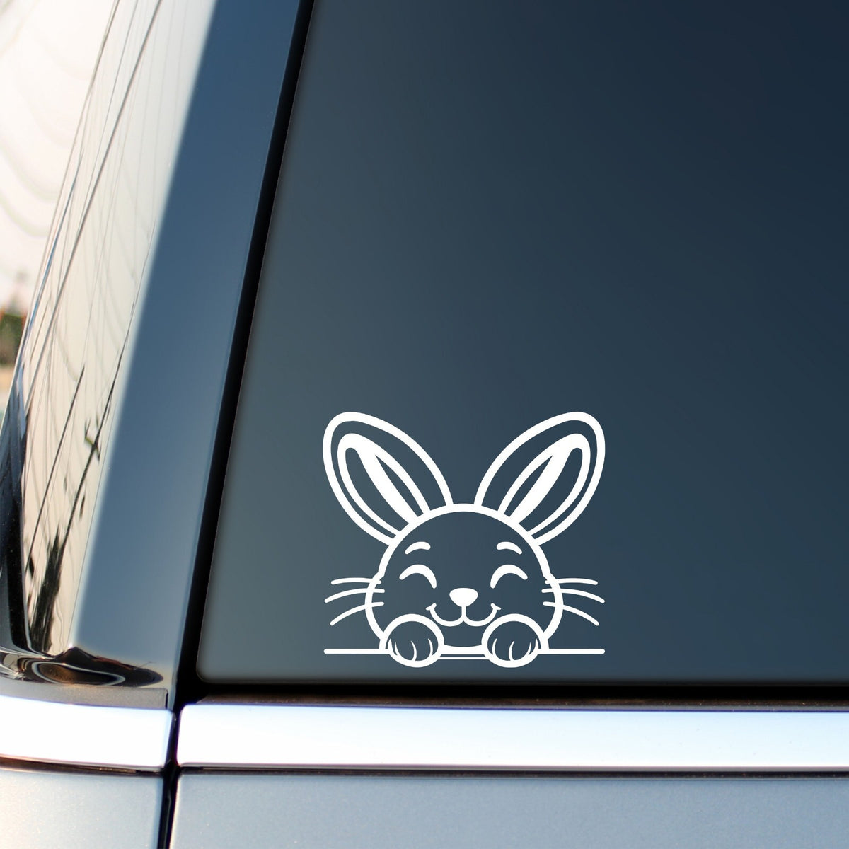 White peeking bunny decal applied at the lower edge of a car side window.