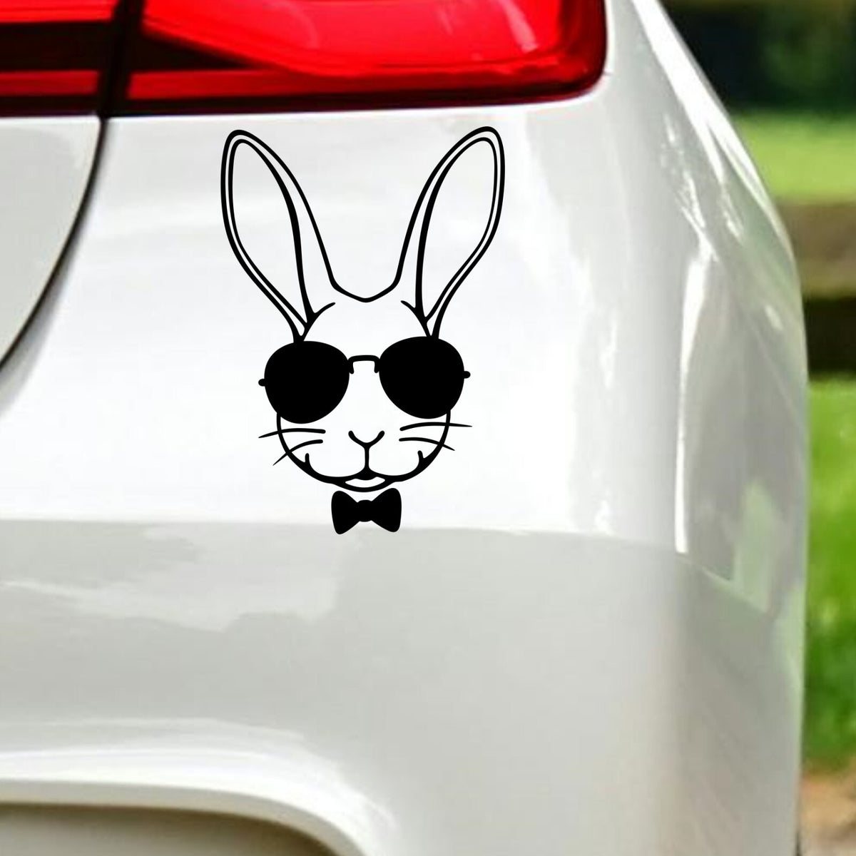 Black rabbit with sunglasses sticker on white car bodywork beneath a rear light.