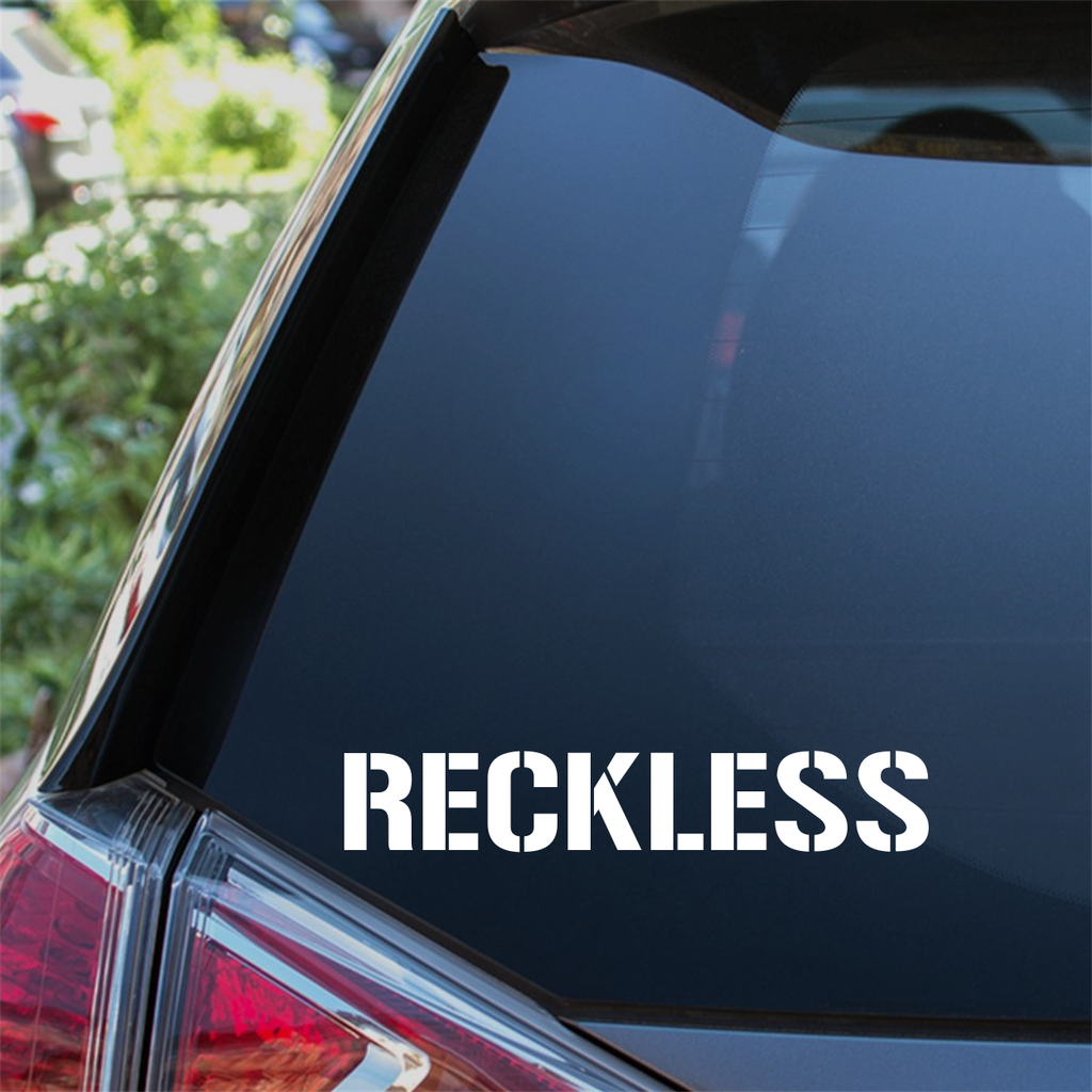 Reckless Stencil Car Sticker in white on a vehicle window.