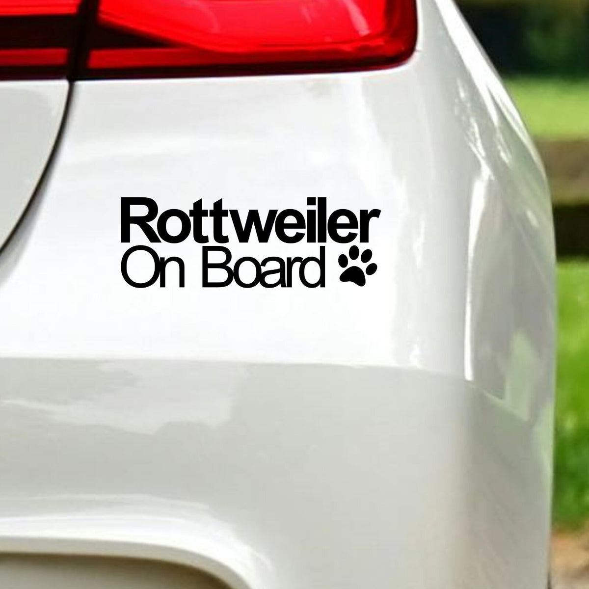 Black Rottweiler On Board decal below the rear light of a white car.