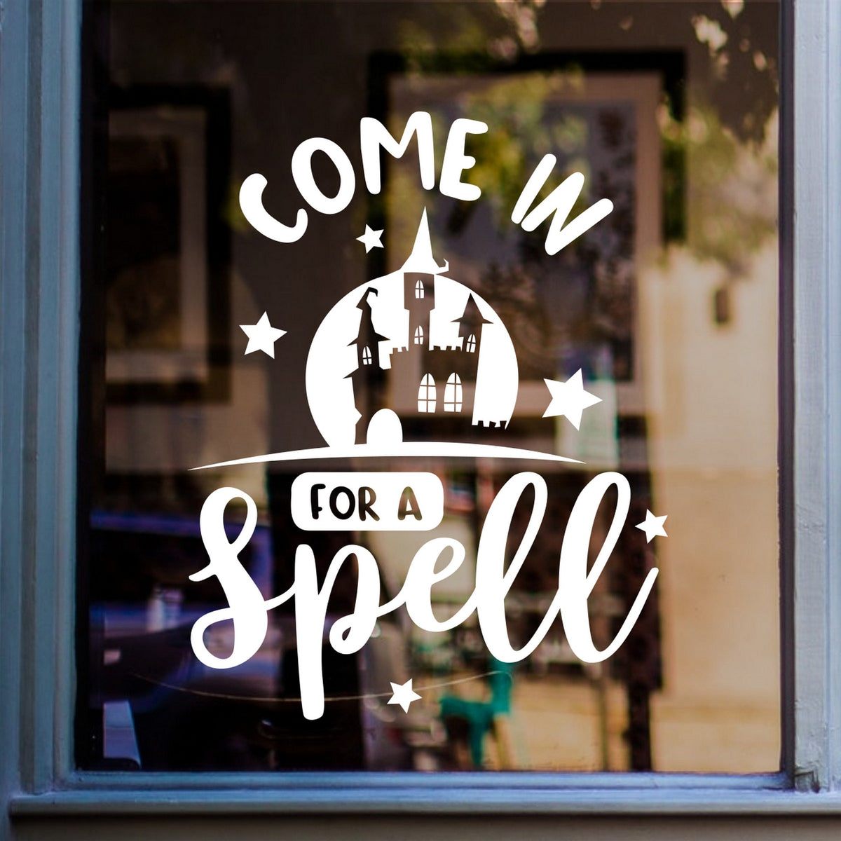 White Come In for a Spell Halloween sticker on a blue-framed café window.
