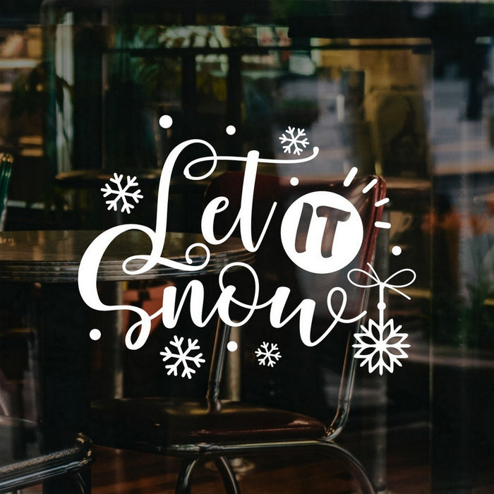 White Let It Snow script window sticker with snowflakes and a hanging ornament on a cafe window.