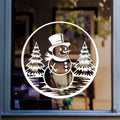Christmas snowman window sticker featuring snowy fir trees in a circular winter scene displayed on glass.