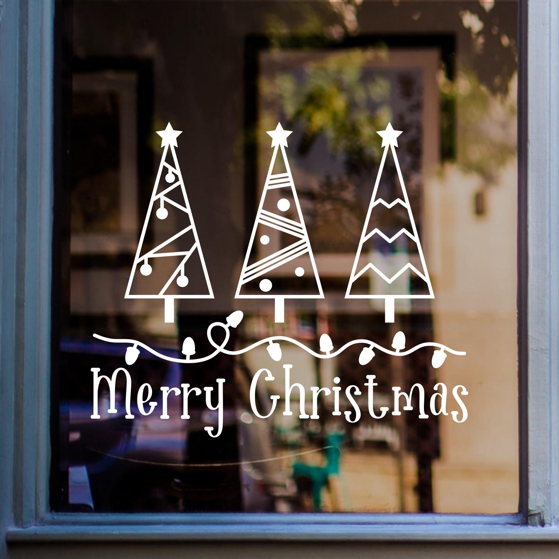 Merry Christmas window sticker featuring three festive Christmas trees with stars displayed on glass.