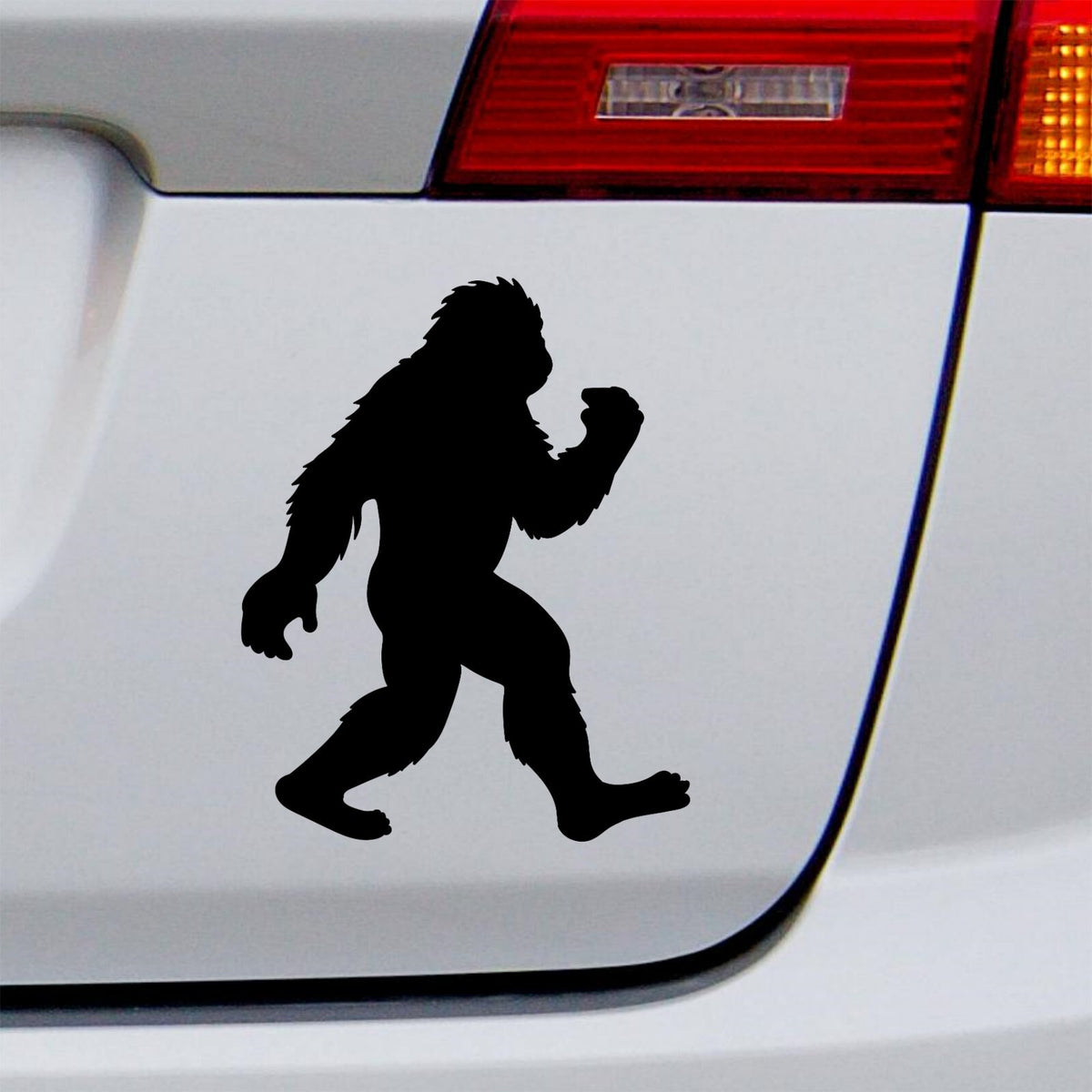 Black walking bigfoot decal on a white vehicle tailgate.