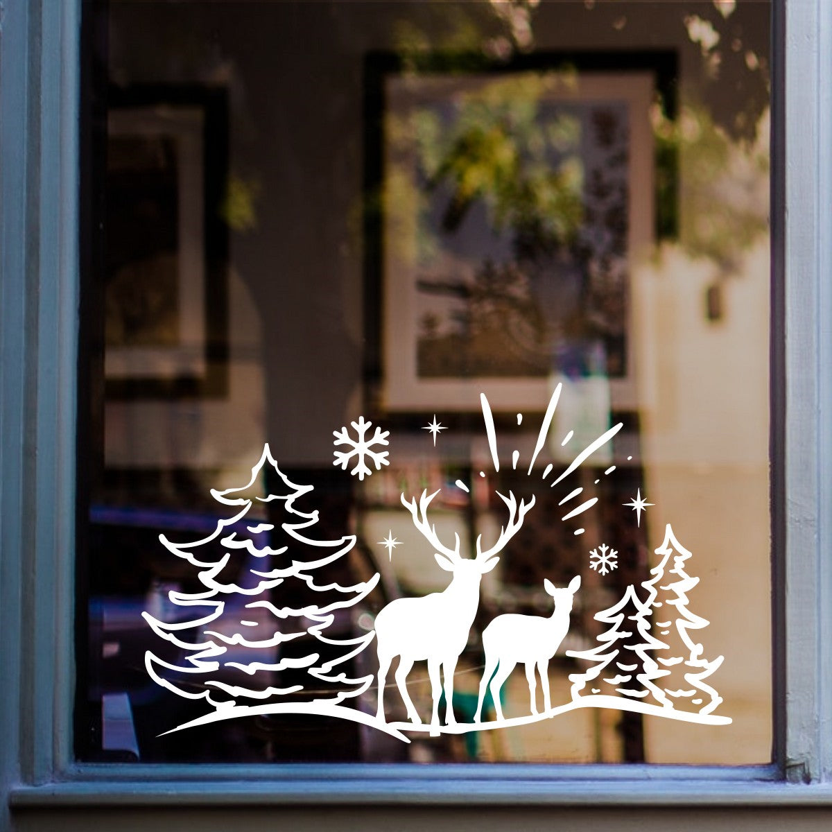 White reindeer and pine tree Christmas scene sticker on a home window