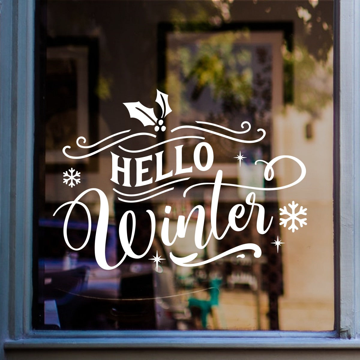 White Hello Winter Christmas window decal with holly and snowflakes on a shop window